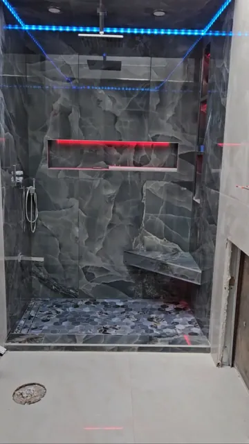 Walk-in shower with lit niche and pebble floor